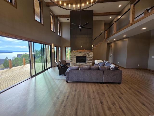 living room featuring a towering ceiling, a fireplace, ceiling fan, and hardwood / wood-style floors