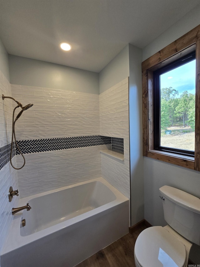 bathroom featuring toilet, tiled shower / bath, and wood-type flooring