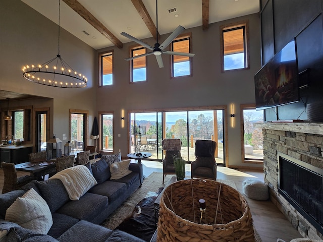 living room featuring ceiling fan with notable chandelier, a high ceiling, a fireplace, and beamed ceiling