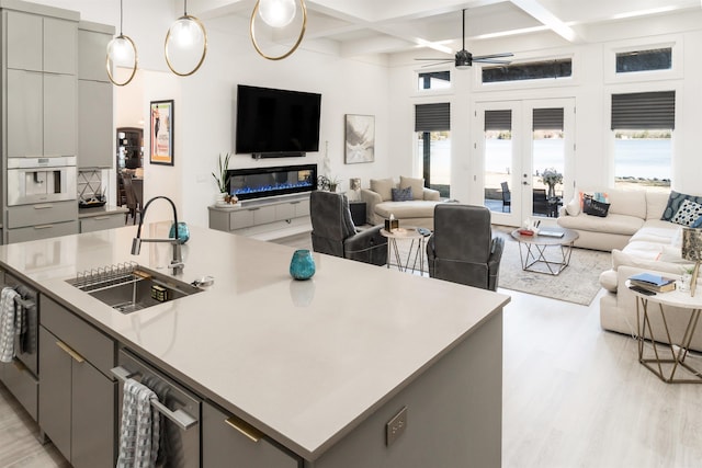 kitchen with sink, an island with sink, french doors, and gray cabinets