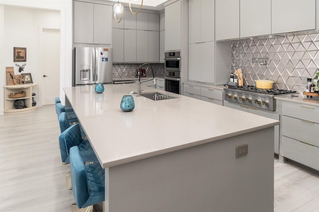 kitchen featuring a spacious island, tasteful backsplash, appliances with stainless steel finishes, a kitchen breakfast bar, and sink