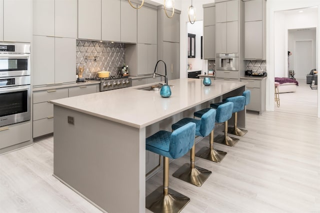 kitchen featuring pendant lighting, a spacious island, a breakfast bar, tasteful backsplash, and sink