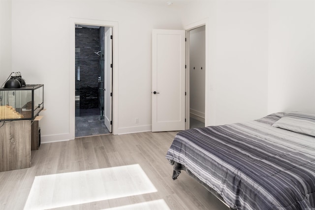 bedroom with ensuite bathroom and light hardwood / wood-style flooring