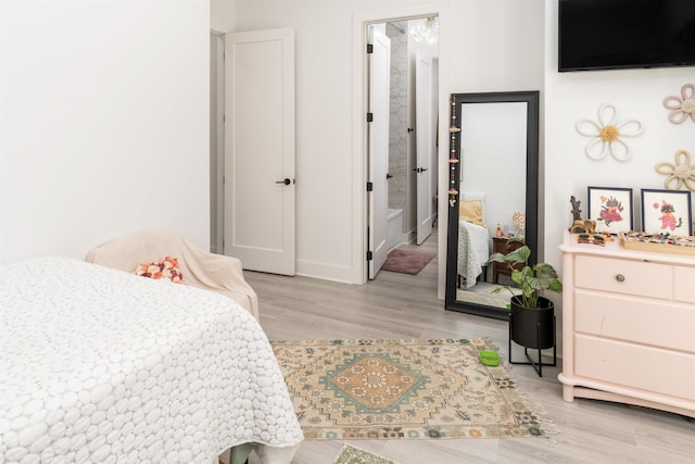 bedroom with light wood-type flooring and connected bathroom