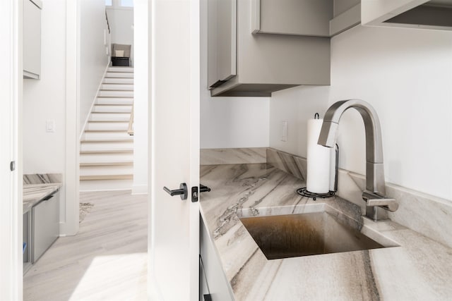 kitchen with sink, gray cabinetry, and light hardwood / wood-style flooring