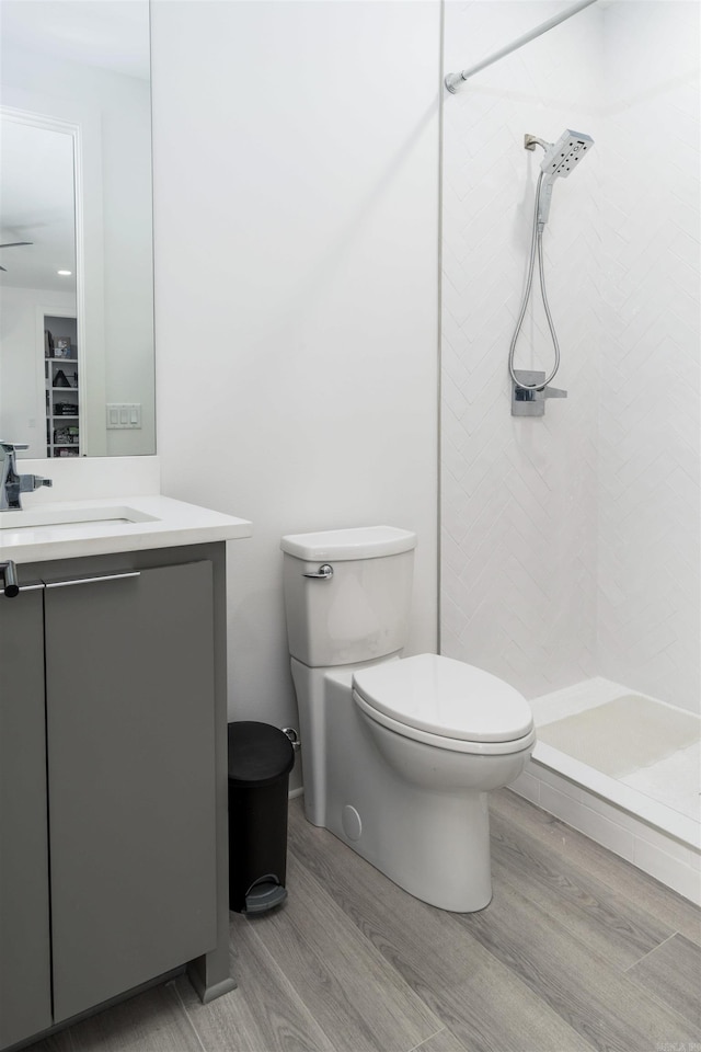 bathroom with toilet, a shower, vanity, and wood-type flooring