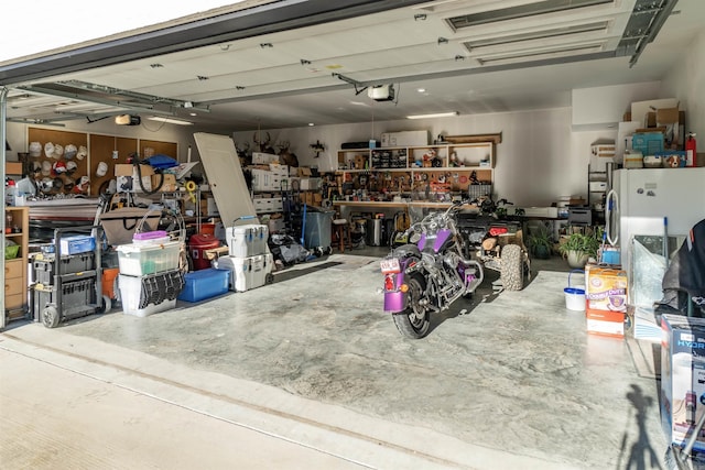 garage with white refrigerator, a workshop area, and a garage door opener