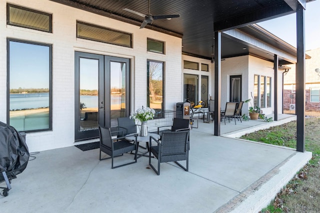 view of patio featuring ceiling fan, french doors, a water view, and an outdoor living space