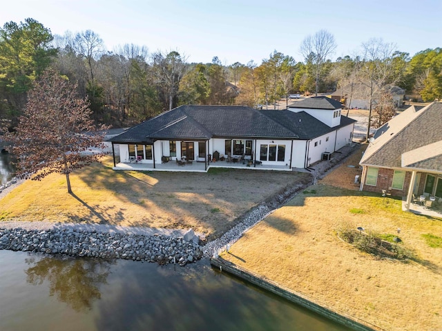 rear view of house featuring a lawn, a patio area, and a water view