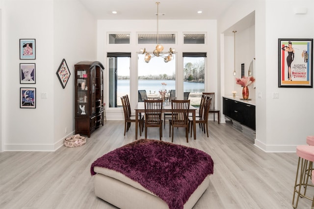 dining space featuring an inviting chandelier, light hardwood / wood-style floors, and a water view