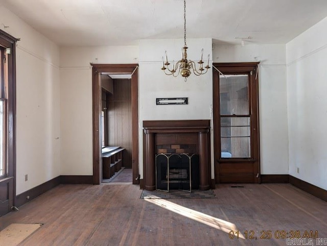 unfurnished living room with an inviting chandelier and dark hardwood / wood-style floors