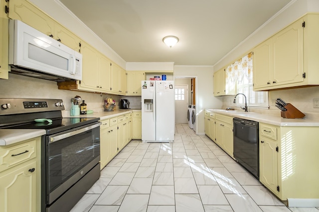 kitchen with white appliances, cream cabinets, sink, and washing machine and clothes dryer