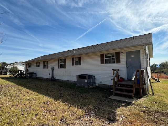 rear view of property with a yard and central AC