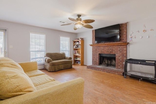 living room featuring a fireplace, light wood-type flooring, and ceiling fan