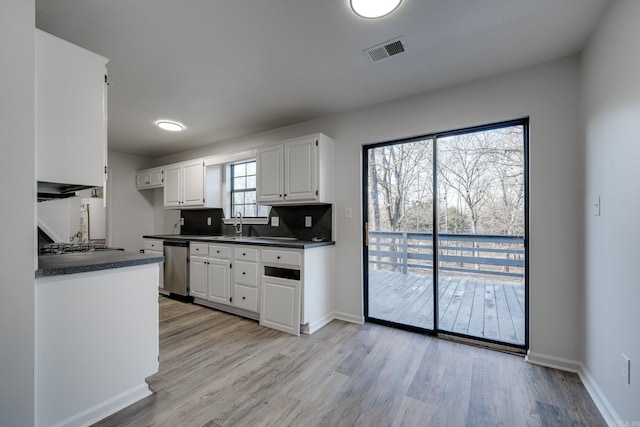 kitchen with white cabinets, dishwasher, light hardwood / wood-style floors, decorative backsplash, and plenty of natural light