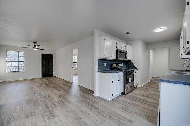 kitchen featuring tasteful backsplash, white cabinetry, appliances with stainless steel finishes, ceiling fan, and sink