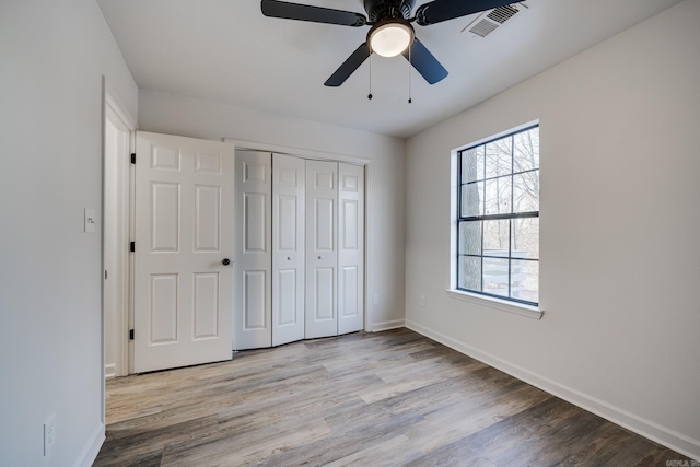 unfurnished bedroom with multiple windows, a closet, ceiling fan, and light wood-type flooring