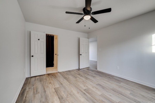 unfurnished bedroom featuring ceiling fan, light wood-type flooring, and a spacious closet