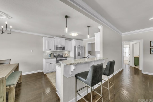 kitchen with decorative light fixtures, white cabinetry, light stone counters, a kitchen bar, and appliances with stainless steel finishes