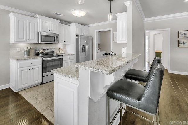 kitchen featuring appliances with stainless steel finishes, white cabinetry, decorative light fixtures, and kitchen peninsula