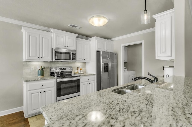 kitchen with stainless steel appliances, washing machine and clothes dryer, white cabinetry, and sink