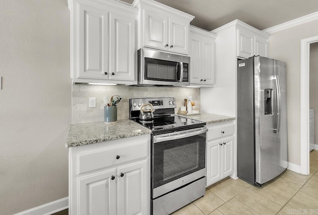 kitchen with appliances with stainless steel finishes, light tile patterned floors, ornamental molding, decorative backsplash, and white cabinets