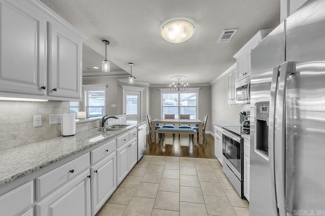 kitchen featuring sink, white cabinets, ornamental molding, pendant lighting, and appliances with stainless steel finishes