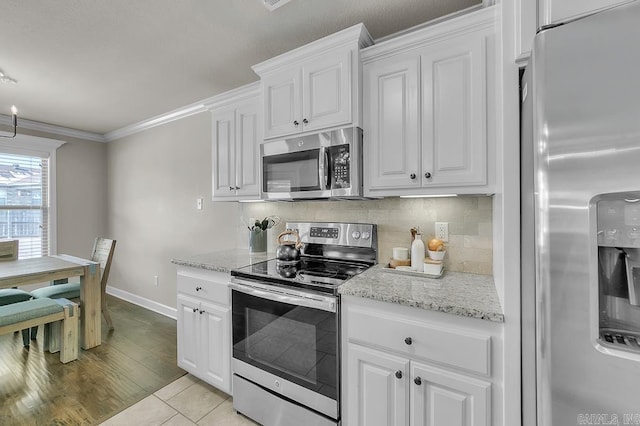 kitchen with stainless steel appliances, light tile patterned floors, ornamental molding, and white cabinets