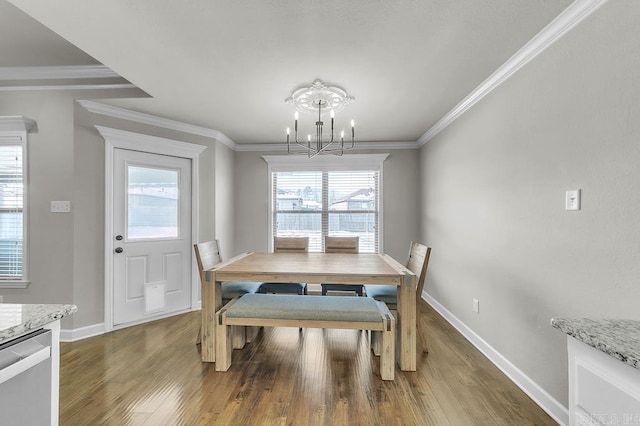 dining space with wood-type flooring, ornamental molding, and a notable chandelier