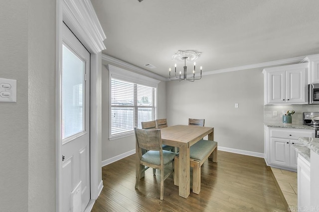 dining space with ornamental molding, light hardwood / wood-style flooring, and a notable chandelier