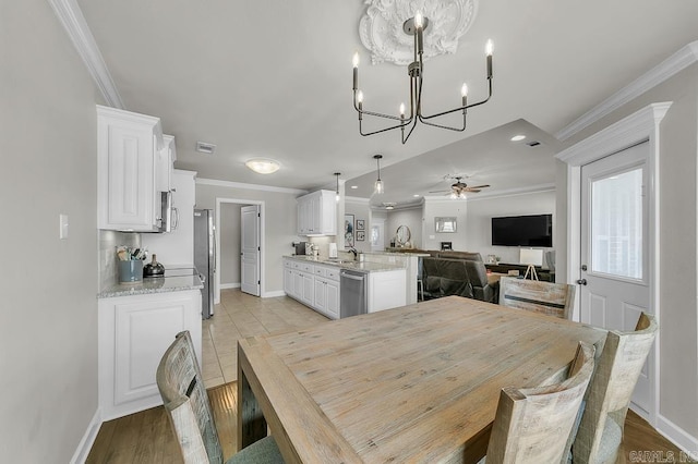 dining space featuring ornamental molding, light hardwood / wood-style floors, sink, and ceiling fan with notable chandelier