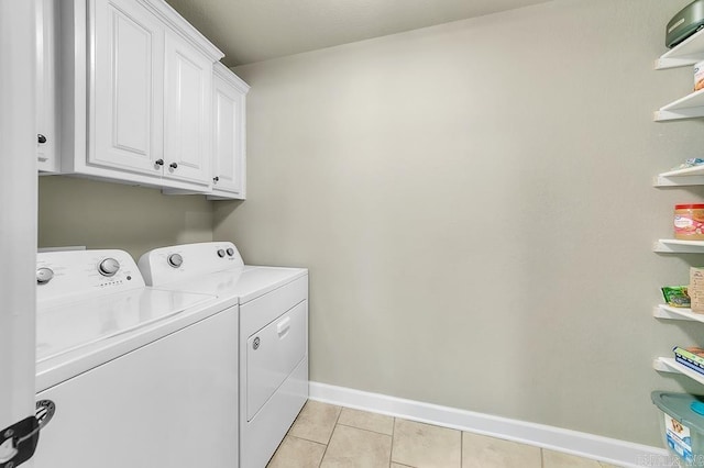 clothes washing area featuring washer and dryer, cabinets, and light tile patterned floors