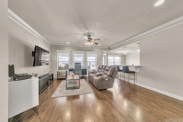 living room featuring ornamental molding, ceiling fan with notable chandelier, and wood-type flooring