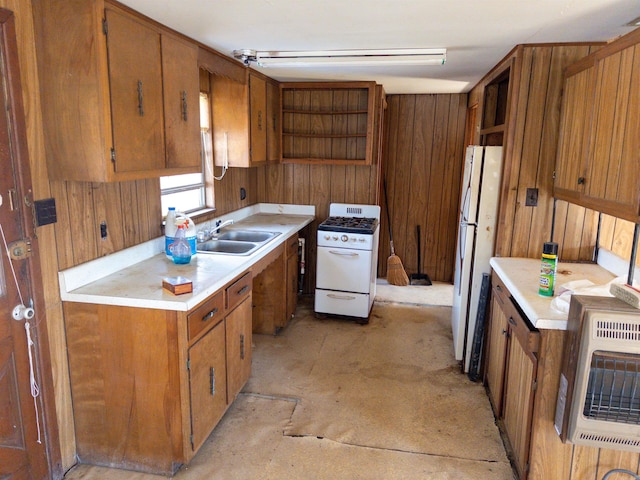 kitchen featuring white appliances, wood walls, heating unit, and sink