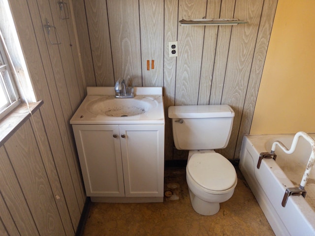 bathroom featuring a bathtub, wood walls, vanity, and toilet