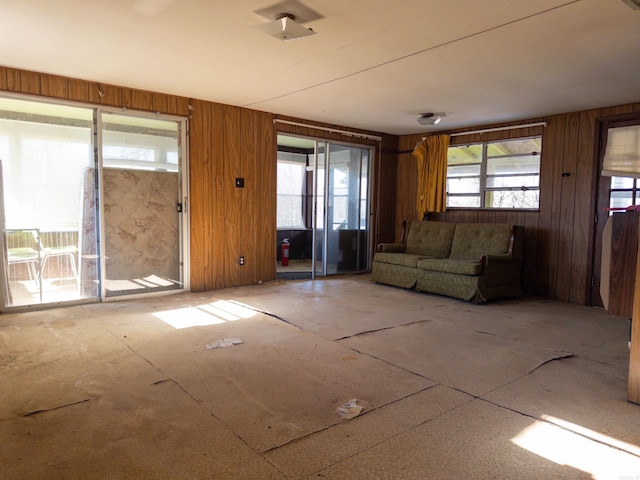 unfurnished living room featuring wood walls