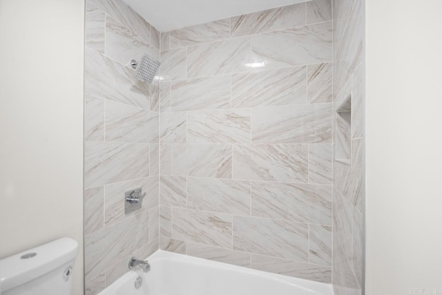 bathroom with tiled shower / bath combo and toilet