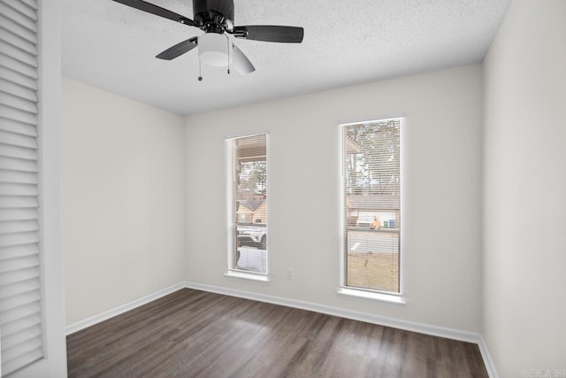 empty room featuring ceiling fan, dark wood-type flooring, and a textured ceiling