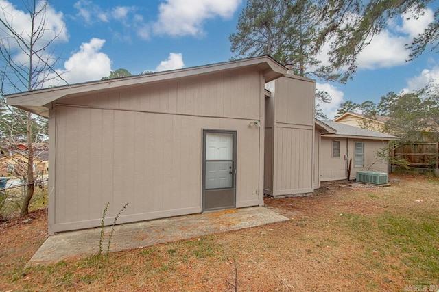 rear view of property featuring central air condition unit and a lawn