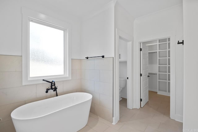 bathroom featuring tile walls, a bathing tub, tile patterned flooring, and toilet