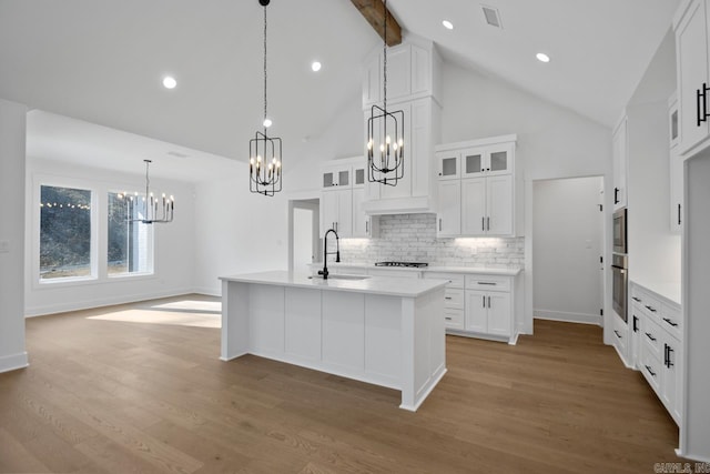 kitchen featuring sink, a kitchen island with sink, tasteful backsplash, and white cabinetry