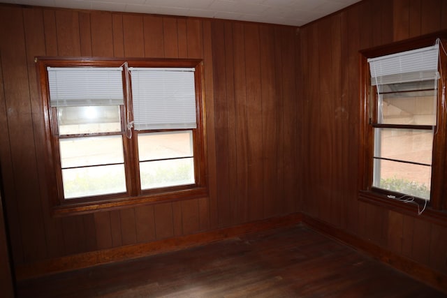 unfurnished room with dark wood-type flooring and wood walls