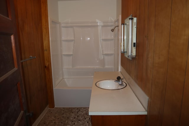 bathroom with vanity, wood walls, and bathing tub / shower combination