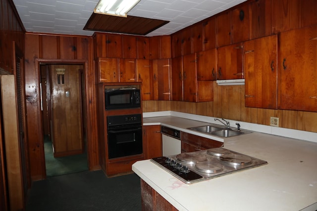 kitchen featuring kitchen peninsula, wooden walls, black appliances, and sink