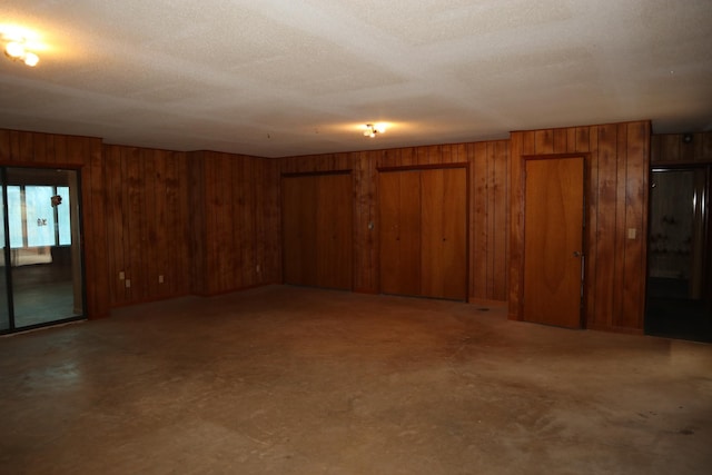 empty room featuring a textured ceiling and wood walls