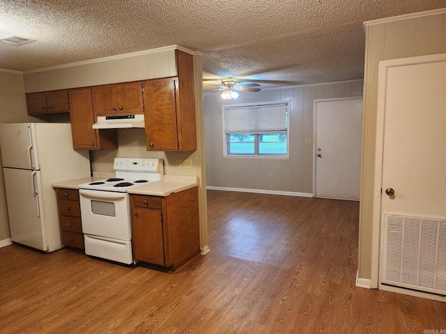 kitchen featuring wooden walls, white appliances, a textured ceiling, and ornamental molding