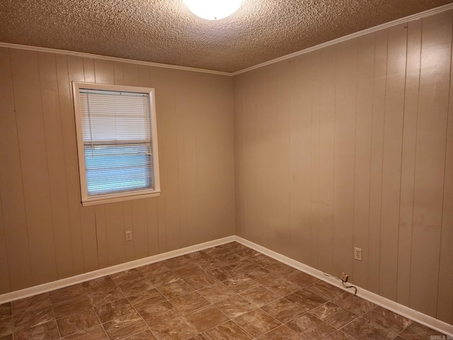 spare room with a textured ceiling, wood walls, and ornamental molding