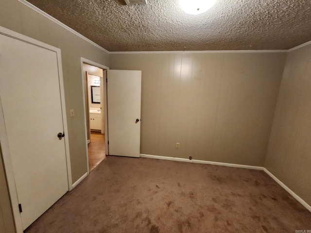 spare room featuring a textured ceiling, crown molding, and carpet flooring