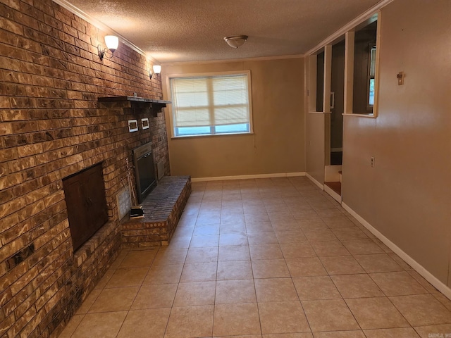 unfurnished living room with a textured ceiling, brick wall, light tile patterned floors, a brick fireplace, and crown molding