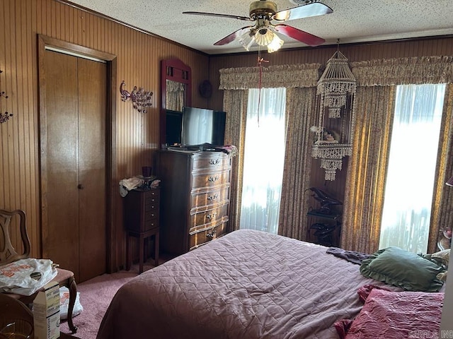 bedroom featuring a textured ceiling, ceiling fan, carpet flooring, and wooden walls